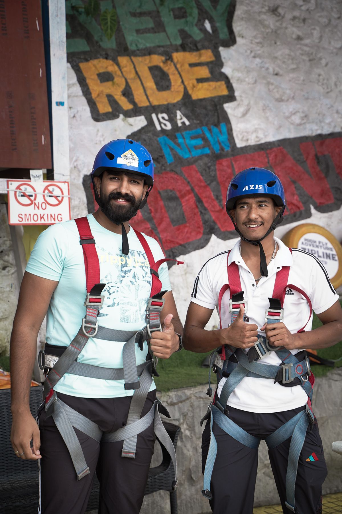 Two guests smiling in helmets and safety harnesses before an activity at High Fly Adventure, Suwakholi