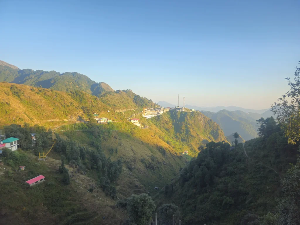 Mussoorie town on its ridge in golden late-afternoon light, with layered hills fading into the November haze