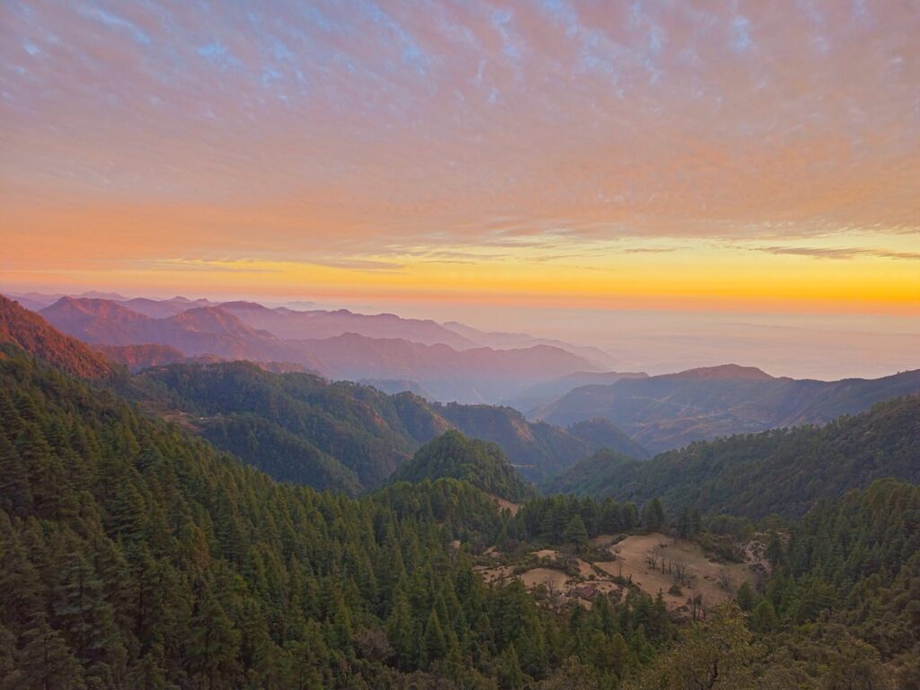 Winterline in Mussoorie: orange and gold false horizon above the plains at sunset, seen over layered hills and forest, shot and edited by The Wimpy's Wrath